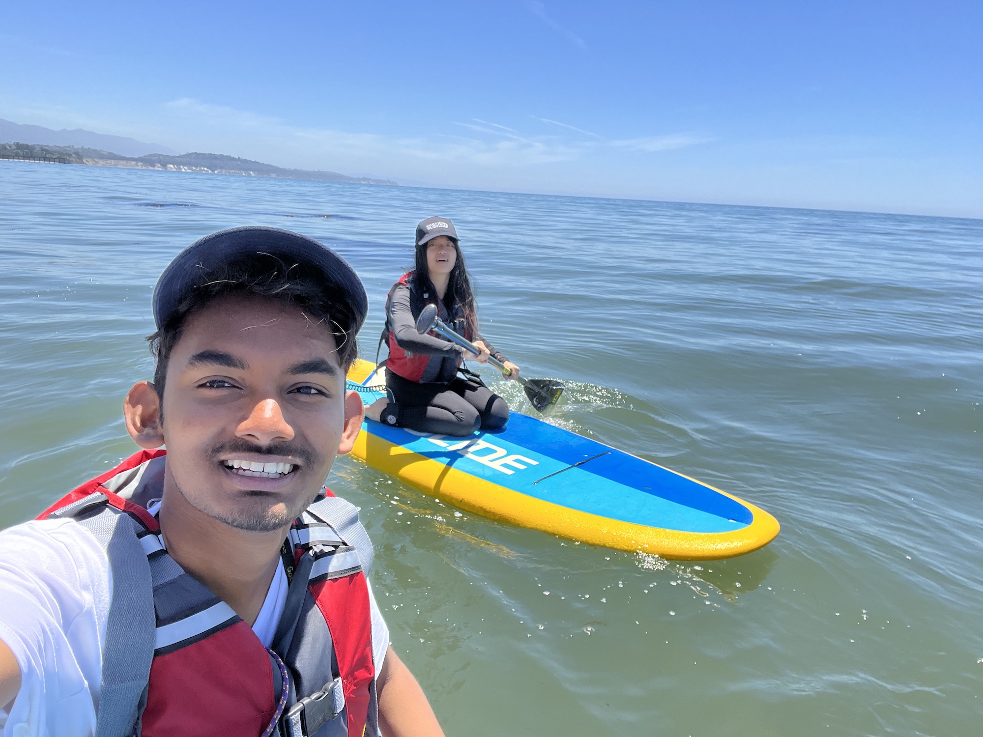 two students sitting on stand up paddle boards in the ocean