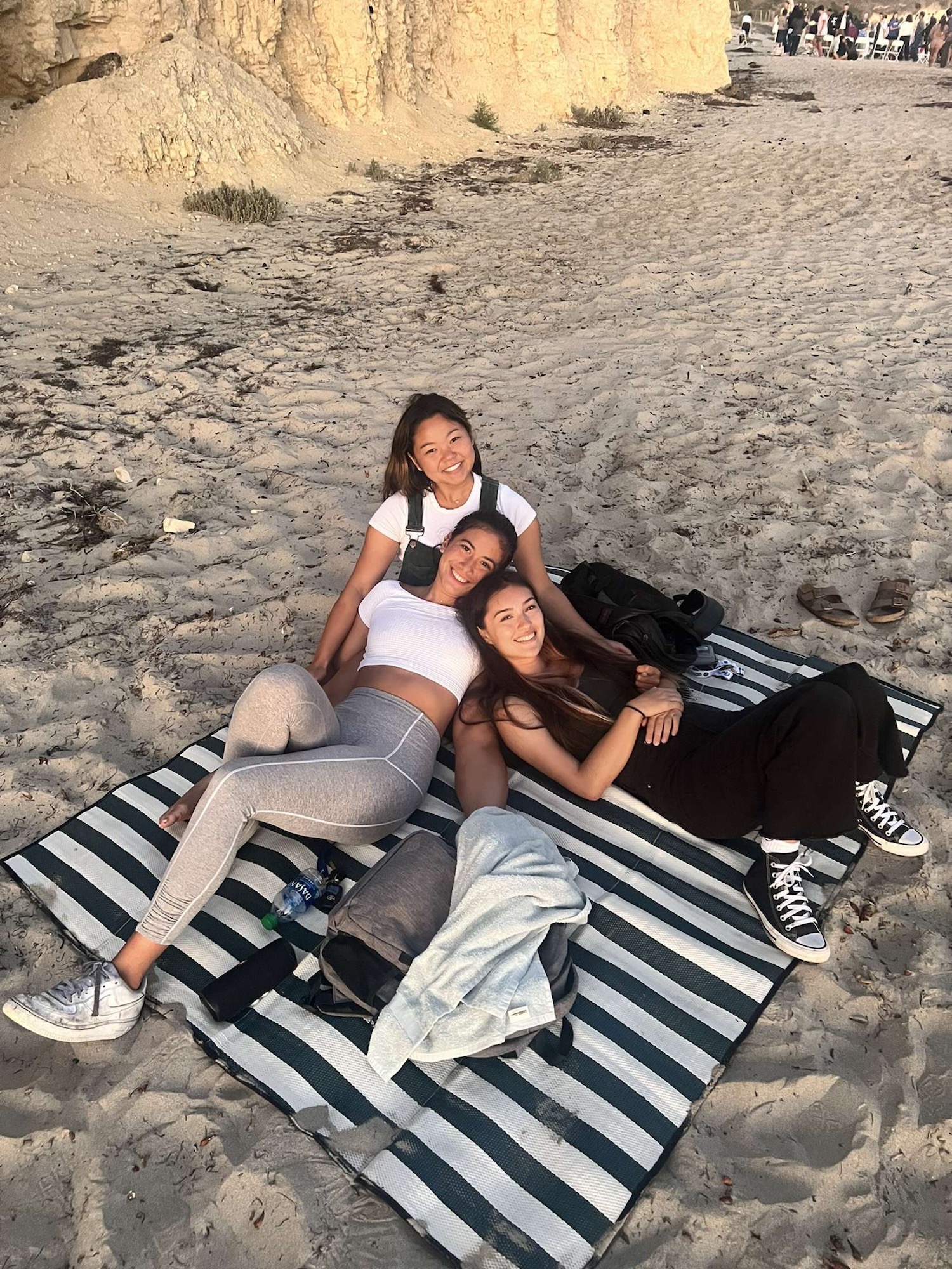 three students lying on each other on a beach towel