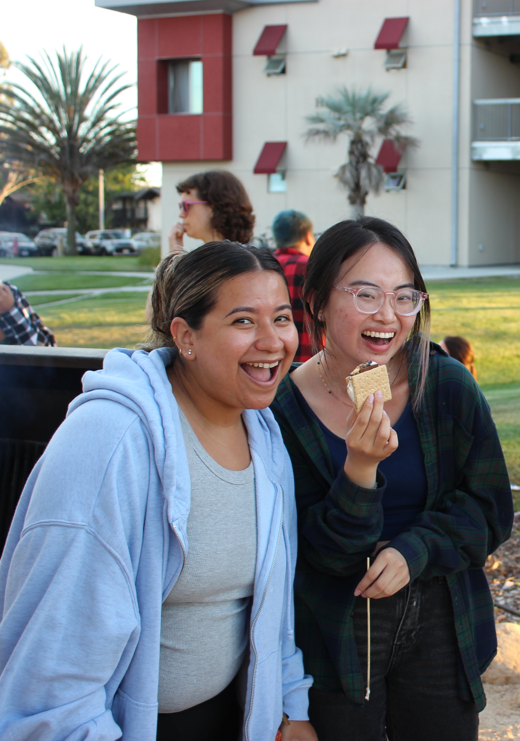 two students laughing and holding a s'mores