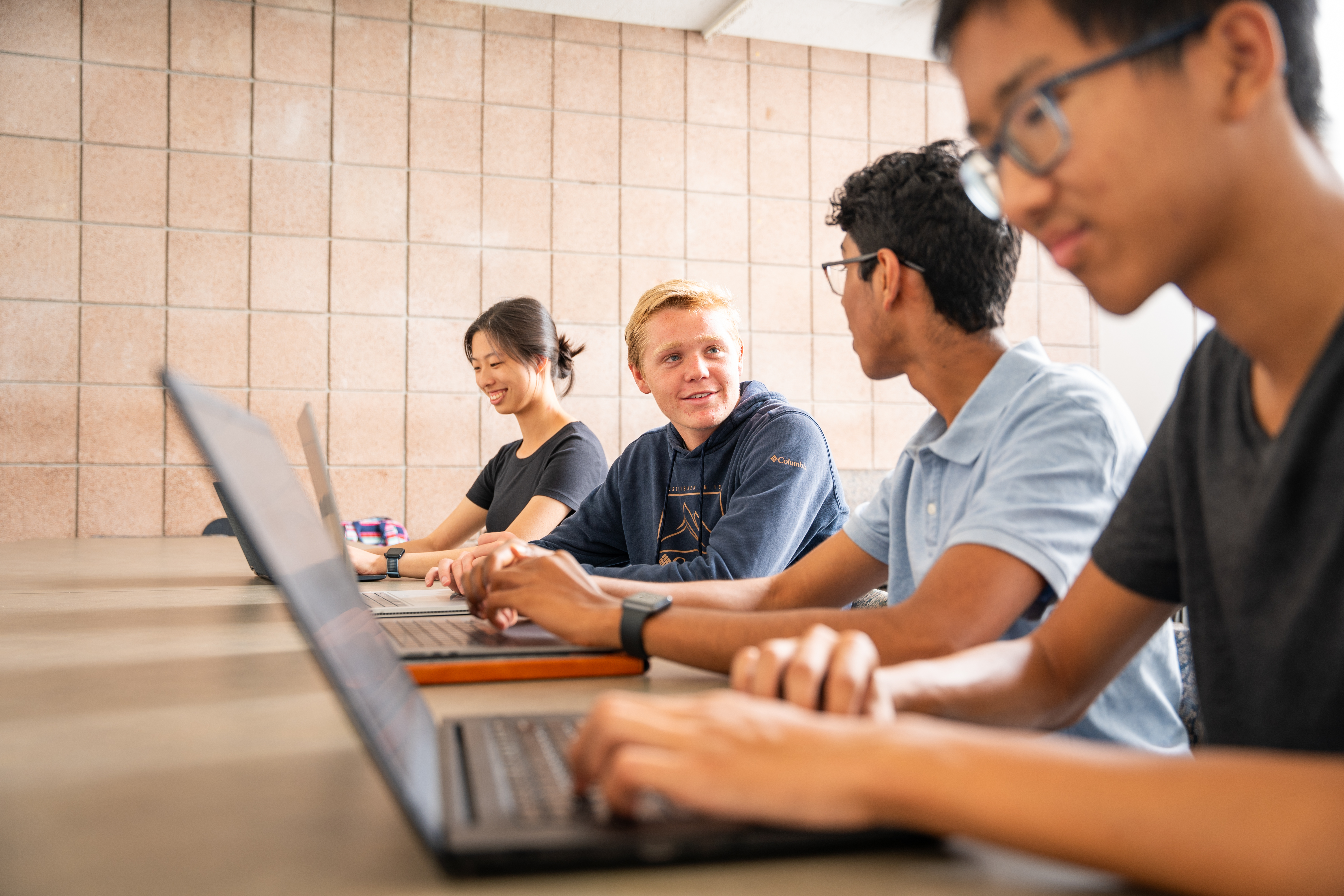 four RMP students on laptops talking