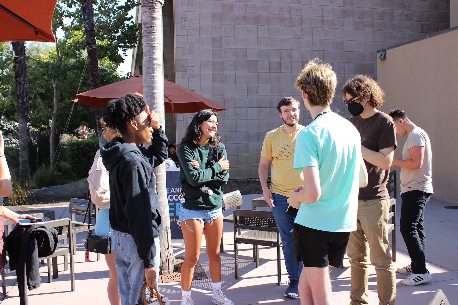 group of students standing in a semi circle outside, listening to another student speak