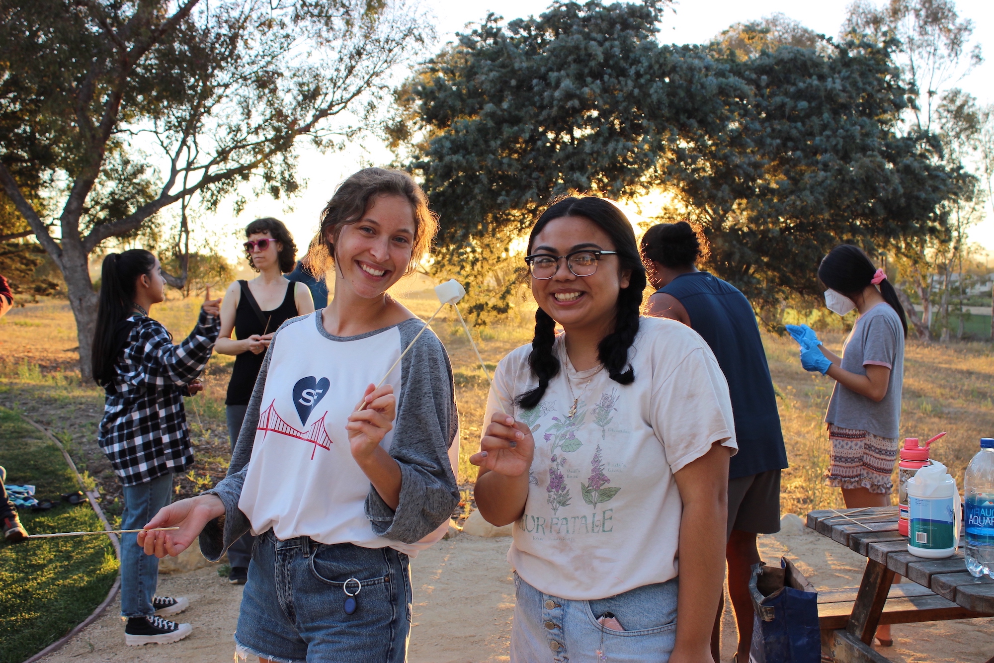two students holding marshmallows on roasting sticks at a fireside chat
