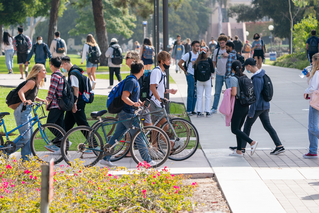 students walking bikes on campus