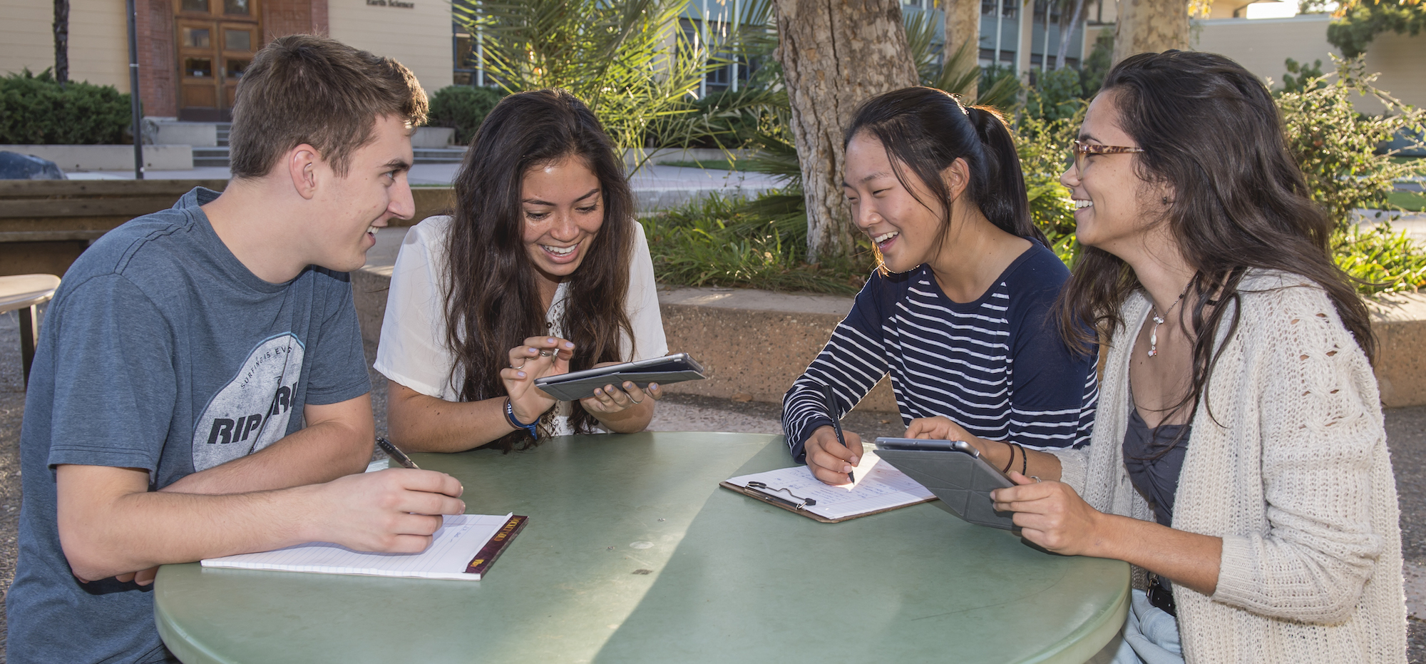 pre-college students sitting around outside table