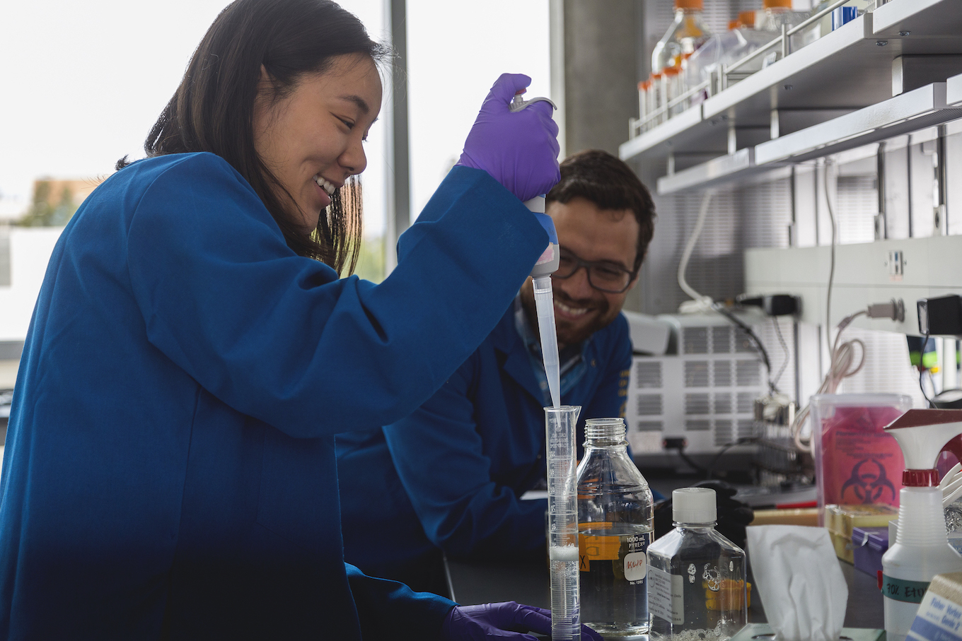 student using pipet, laughing with peer