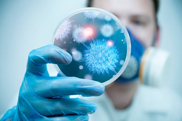 scientist in mask holding up specimen