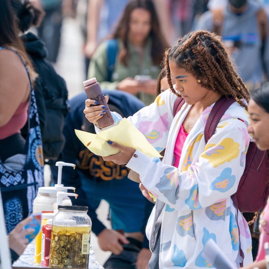 student dressing food at booth